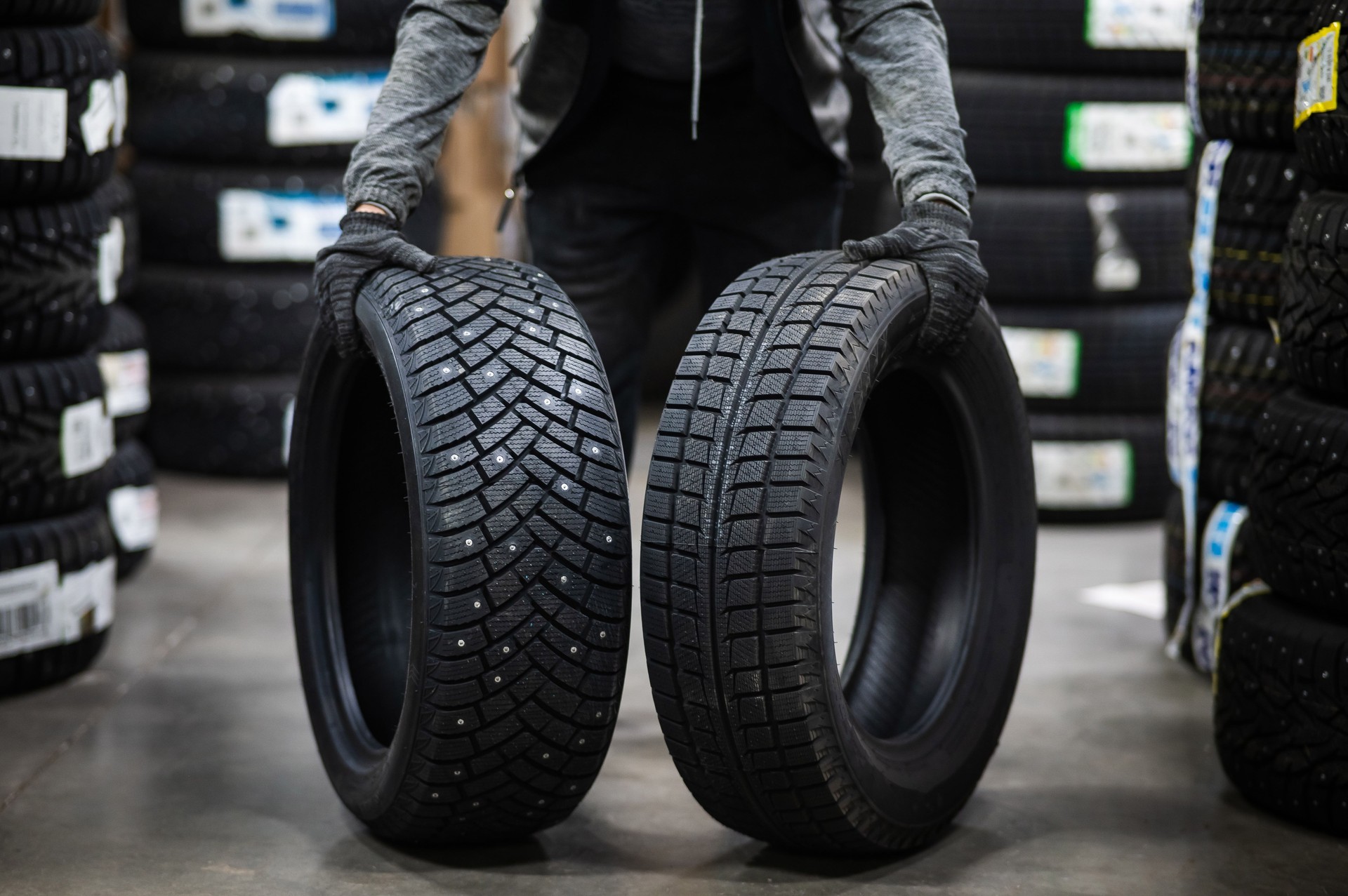 Mechanic keeps new summer and winter car tires in the garage. Comparison of wheels for different seasons.